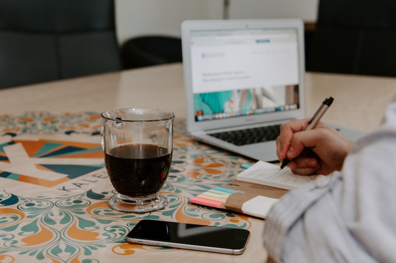 This is photo of someone drinking coffee and making a marketing strategy. Every business owner needs a marketing strategy.